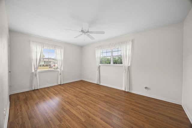 empty room with ceiling fan and dark hardwood / wood-style flooring