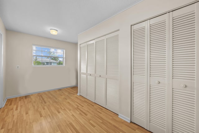 unfurnished bedroom featuring light hardwood / wood-style floors and two closets