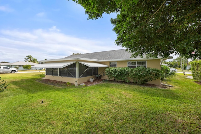 back of property with a lawn and a sunroom