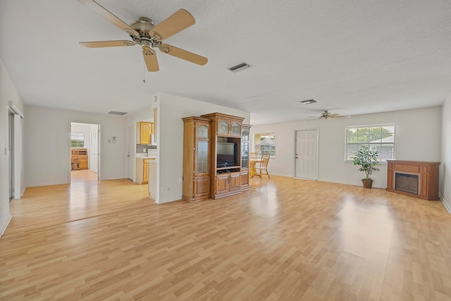 unfurnished living room featuring a textured ceiling, light hardwood / wood-style flooring, and ceiling fan