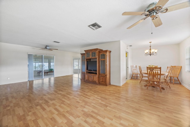 unfurnished living room featuring ceiling fan with notable chandelier, a textured ceiling, and light wood-type flooring