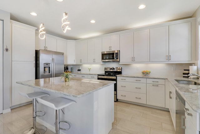 kitchen featuring white cabinetry, sink, a kitchen island, and appliances with stainless steel finishes