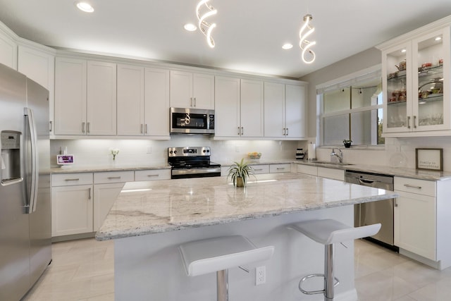 kitchen featuring white cabinets, decorative light fixtures, and appliances with stainless steel finishes