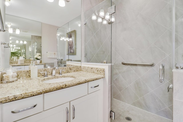 bathroom featuring a shower with door and vanity