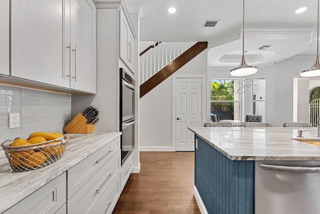 kitchen with white cabinets, hanging light fixtures, decorative backsplash, light stone countertops, and dark hardwood / wood-style flooring