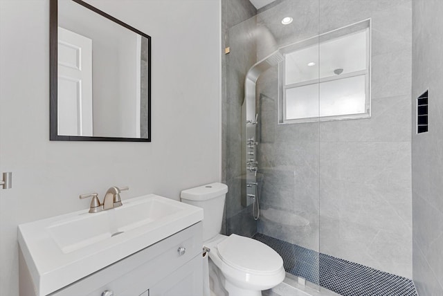 bathroom with tiled shower, vanity, and toilet