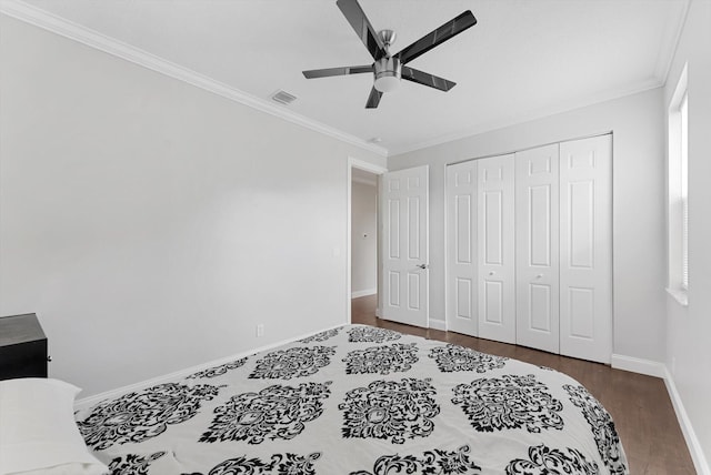 bedroom with a closet, ceiling fan, crown molding, and dark hardwood / wood-style floors