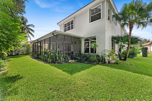 rear view of house with a sunroom and a yard