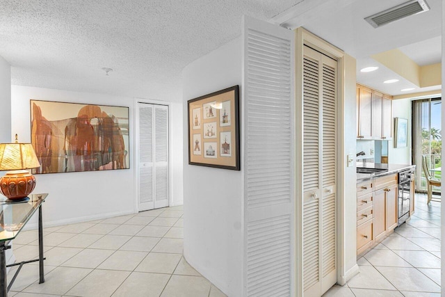 hallway with light tile patterned floors, a textured ceiling, and sink