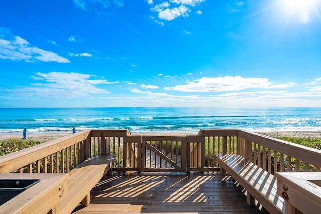 wooden terrace featuring a water view and a view of the beach