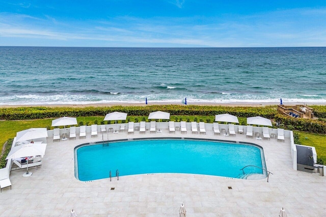 view of pool with a water view, a patio, and a view of the beach