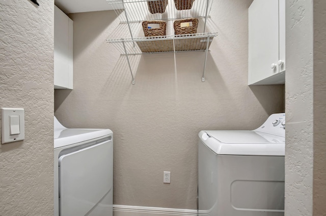 clothes washing area with cabinets and washer and dryer