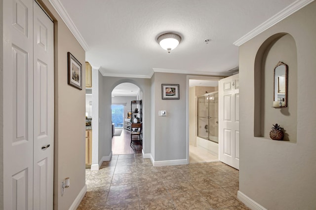 corridor with ornamental molding and a textured ceiling