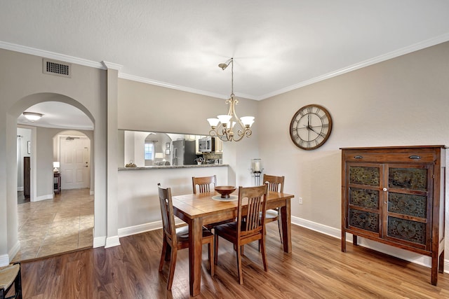 dining area featuring hardwood / wood-style flooring, ornamental molding, and a chandelier