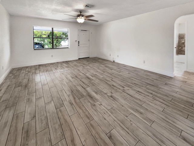 empty room with ceiling fan, light hardwood / wood-style floors, and a textured ceiling