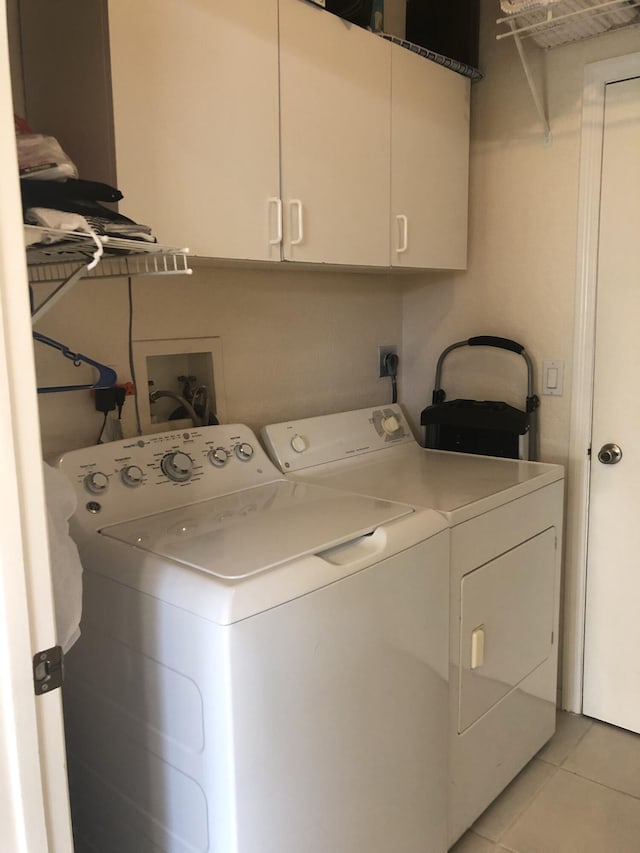 laundry area with washer and clothes dryer, light tile patterned flooring, and cabinets