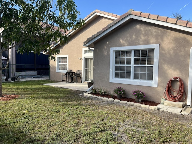 back of property featuring a lawn and a patio