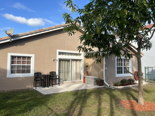 rear view of property featuring a lawn and a patio area