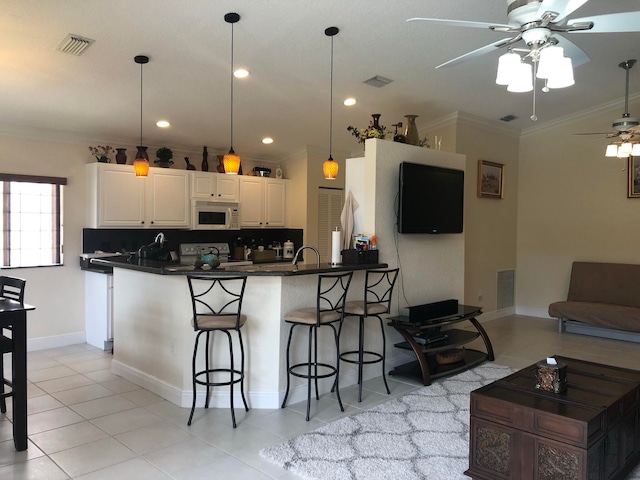 kitchen featuring white cabinets, white appliances, hanging light fixtures, and ornamental molding