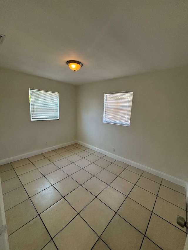 spare room featuring baseboards, light tile patterned floors, and visible vents