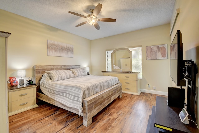 bedroom with a textured ceiling, light hardwood / wood-style flooring, and ceiling fan