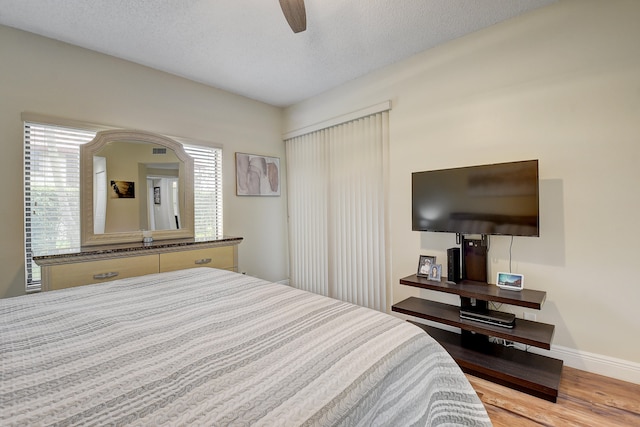 bedroom with ceiling fan, a textured ceiling, and light wood-type flooring