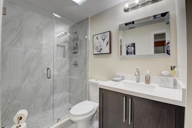 bathroom featuring a shower with door, vanity, and toilet