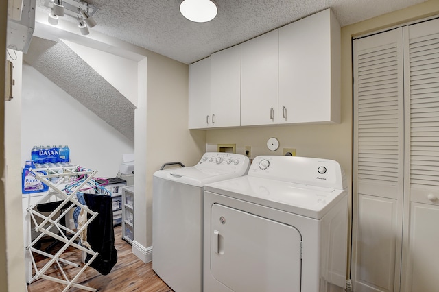 washroom with separate washer and dryer, light hardwood / wood-style flooring, cabinets, and a textured ceiling