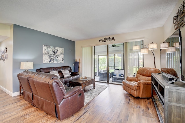 living room with a textured ceiling, light hardwood / wood-style flooring, and ceiling fan