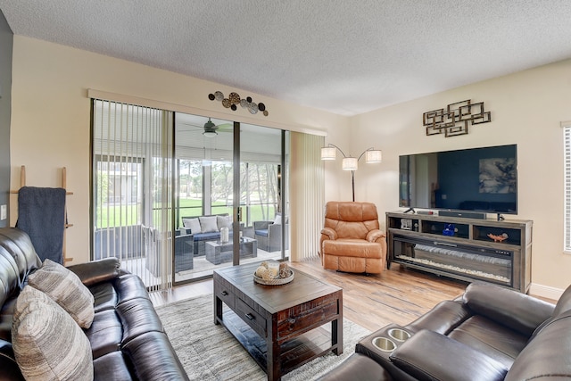 living room with ceiling fan, wood-type flooring, and a textured ceiling