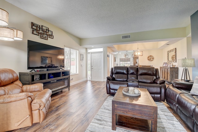 living room featuring an inviting chandelier, a textured ceiling, and hardwood / wood-style flooring