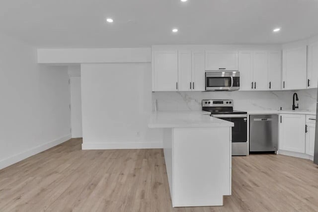 kitchen with decorative backsplash, appliances with stainless steel finishes, light wood-type flooring, sink, and white cabinetry