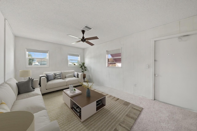 carpeted living room featuring ceiling fan and a textured ceiling