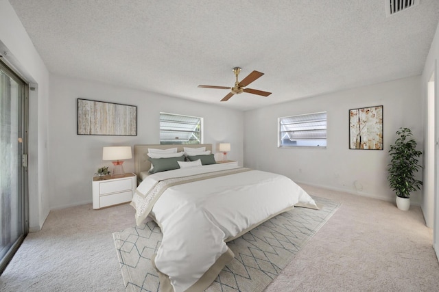 bedroom with ceiling fan, light carpet, and a textured ceiling