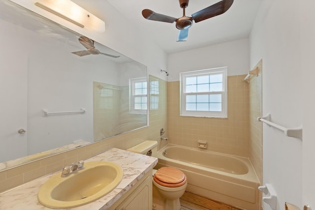 full bathroom with ceiling fan, vanity, toilet, and tiled shower / bath combo