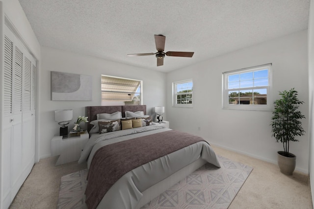 carpeted bedroom featuring ceiling fan, a closet, and a textured ceiling