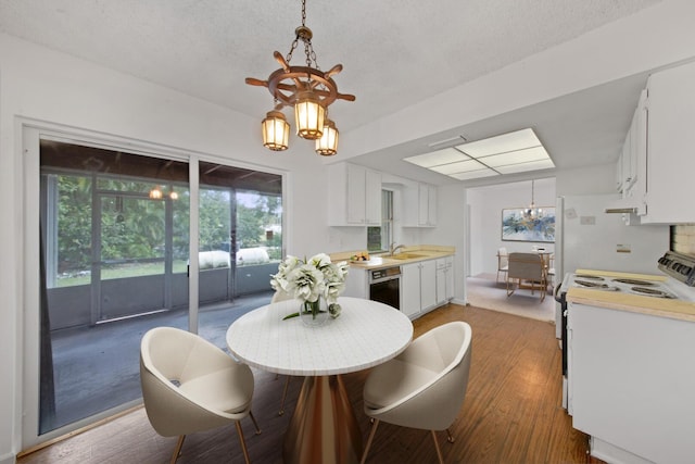 dining space featuring a textured ceiling, sink, hardwood / wood-style floors, and a notable chandelier