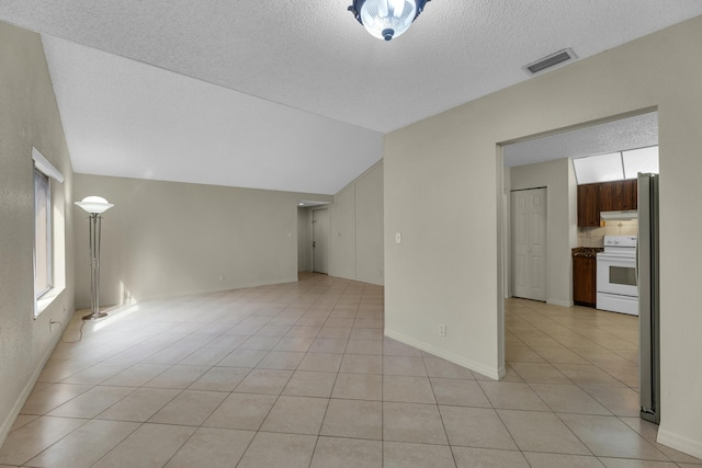 unfurnished living room with light tile patterned flooring, a textured ceiling, and vaulted ceiling