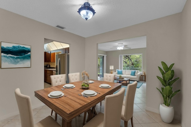 tiled dining space featuring a textured ceiling and ceiling fan