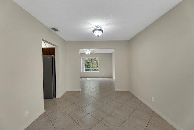 spare room with ceiling fan, light tile patterned floors, and a textured ceiling