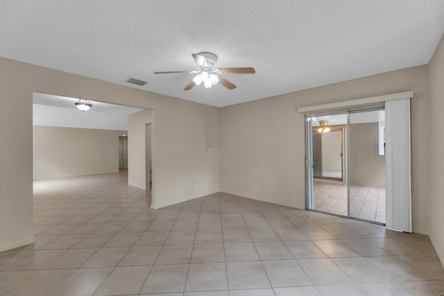 empty room featuring ceiling fan, light tile patterned floors, and a textured ceiling