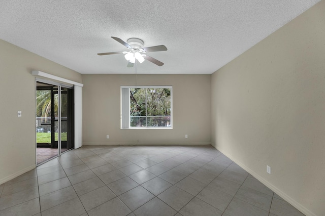 tiled spare room with a textured ceiling, ceiling fan, and a healthy amount of sunlight