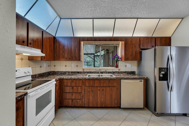 kitchen with backsplash, sink, a skylight, light tile patterned floors, and appliances with stainless steel finishes