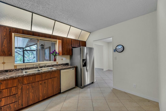 kitchen with a textured ceiling, stainless steel appliances, sink, lofted ceiling, and light tile patterned flooring