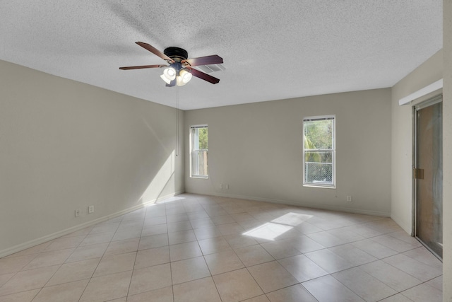 tiled spare room with a textured ceiling, ceiling fan, and a healthy amount of sunlight