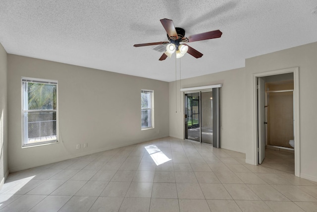 tiled empty room with ceiling fan and a textured ceiling