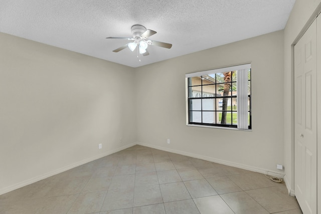 spare room with ceiling fan, light tile patterned floors, and a textured ceiling