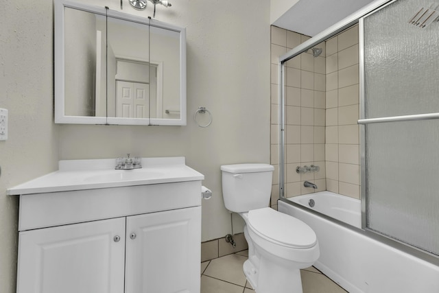 full bathroom featuring toilet, vanity, tile patterned floors, and bath / shower combo with glass door