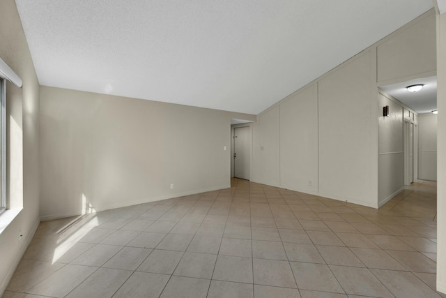 spare room with light tile patterned floors and lofted ceiling