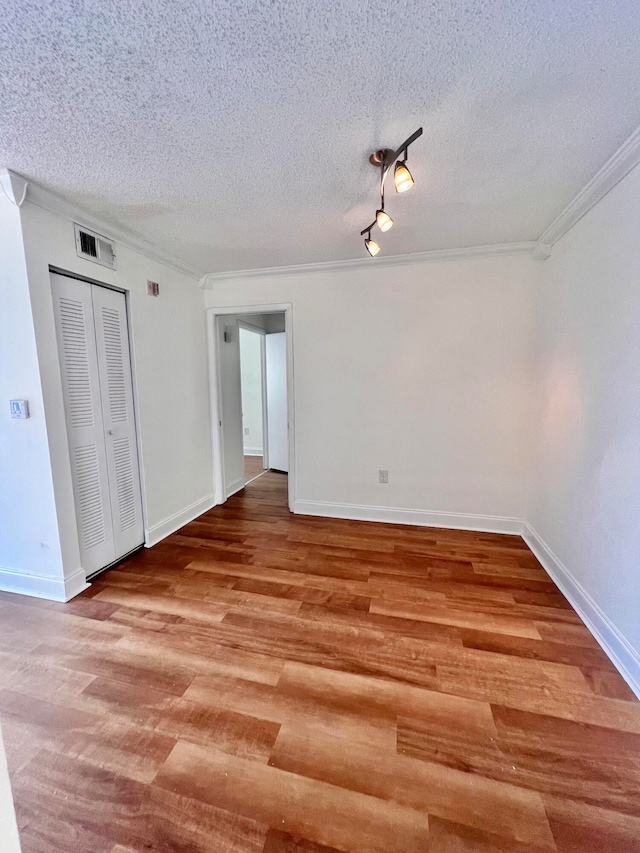 unfurnished bedroom with a textured ceiling, hardwood / wood-style flooring, a closet, and ornamental molding